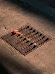 Two workers in safety gear installing heavy metal trench drain grates in a commercial parking lot.