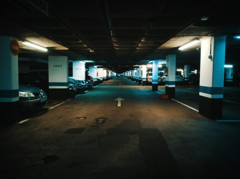 A commercial parking garage ramp with a metal trench grate collecting rainwater near the bottom of the slope